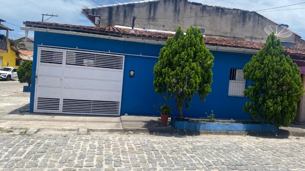 een blauw huis met een witte garagedeur en twee bomen bij Nunes stay in Prado