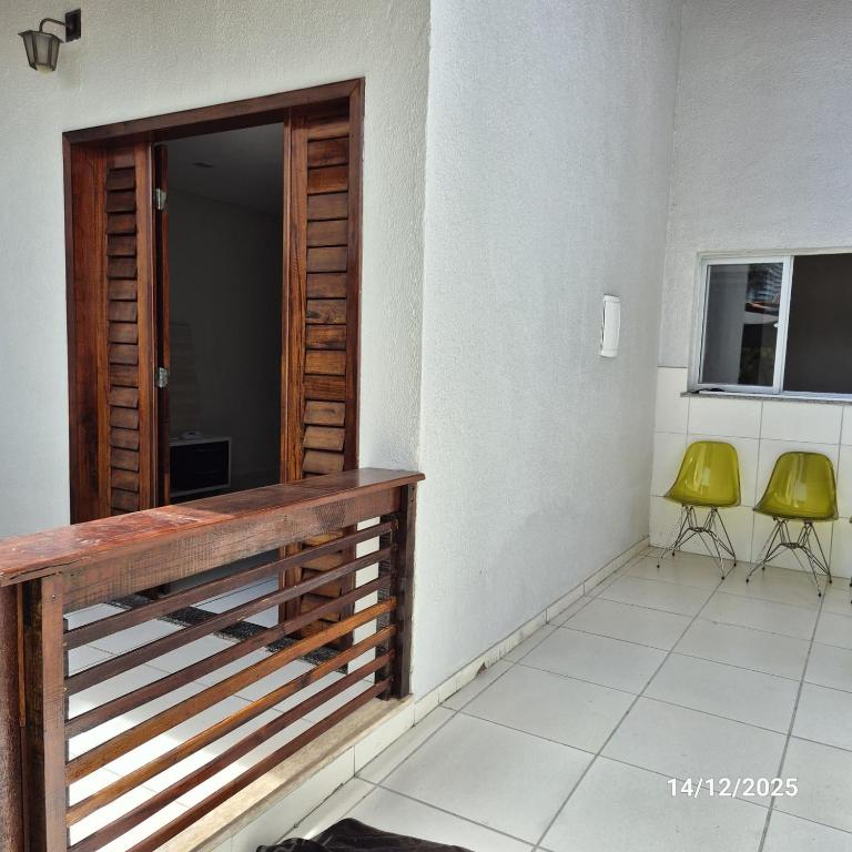 Casa de Condomínio Privativo في فورتاليزا: بلكونه فيها باب خشبي وكرسيين