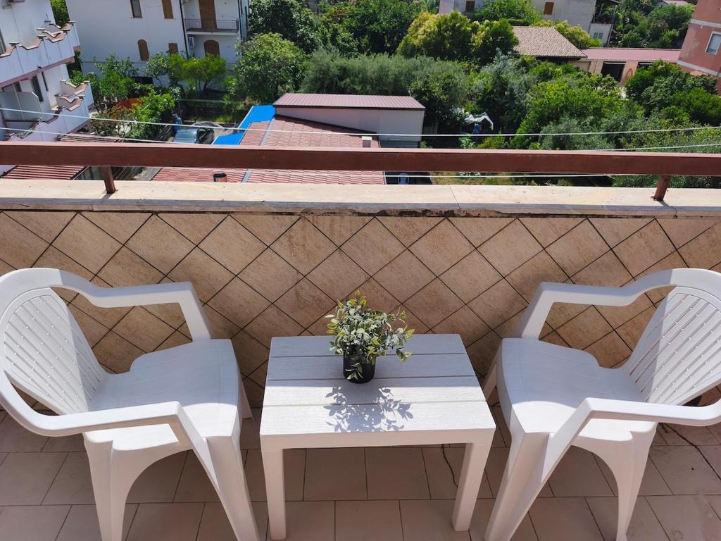 drei weiße Stühle und ein Tisch auf einem Balkon in der Unterkunft Casa Diana in Scalea