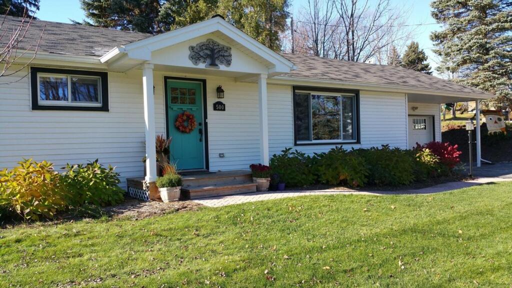 a house with a blue door and a lawn at Against the Wind Vacation Rental LLC in Lake Leelanau