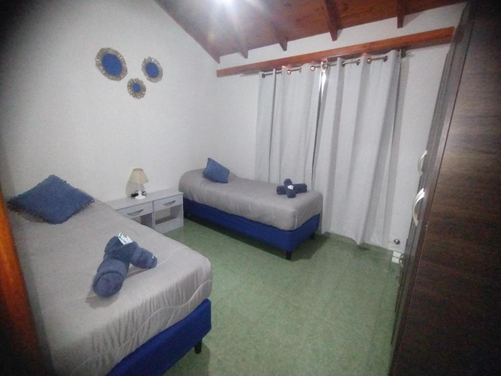 Un dormitorio con dos camas con almohadas azules. en cabaña refugio junto al cerro, en San Luis