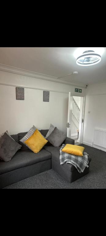 een woonkamer met een zwarte bank met gele kussens bij Grove manor in Streatham Vale