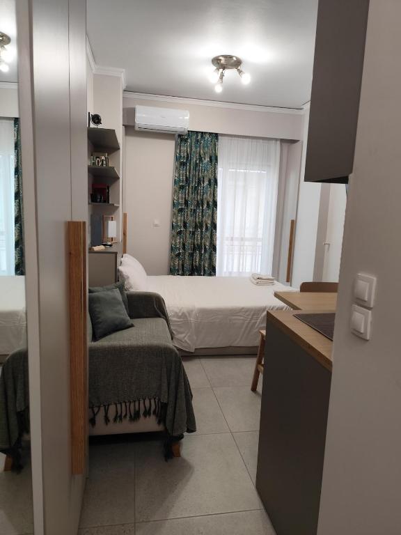 a bedroom with a bed and a couch and a window at Parastaseis Central Studio Georges Sq in Patra