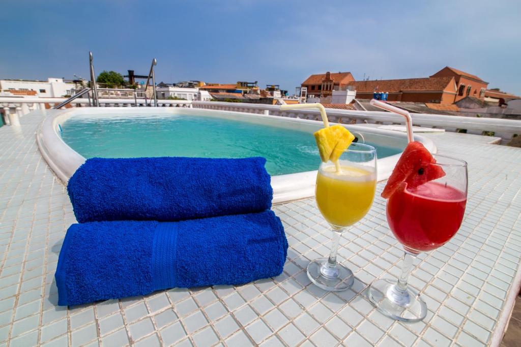 a table with two glasses of drinks next to a swimming pool at Hotel 3 Banderas in Cartagena de Indias