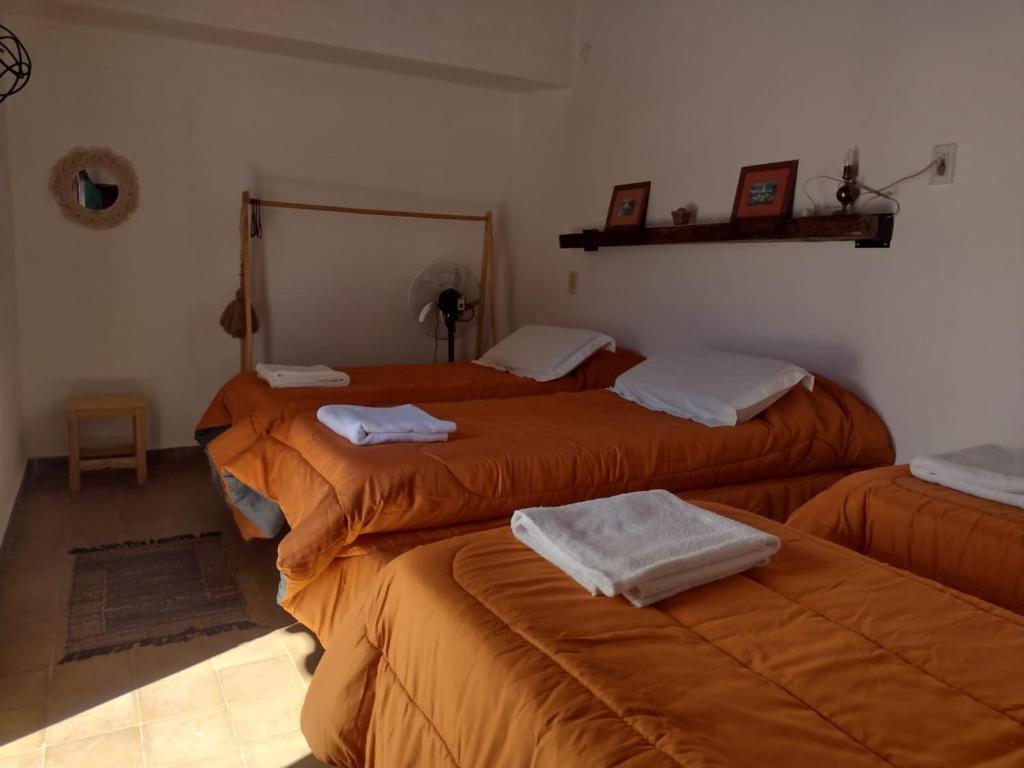een kamer met 2 bedden met oranje lakens bij El Rincón de las Palmas in Cafayate