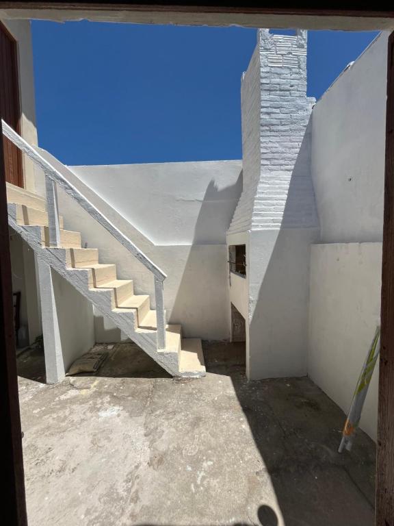 eine Treppe in einem weißen Gebäude mit blauem Himmel in der Unterkunft Casa Praia do Hermenegildo in Santa Vitória do Palmar
