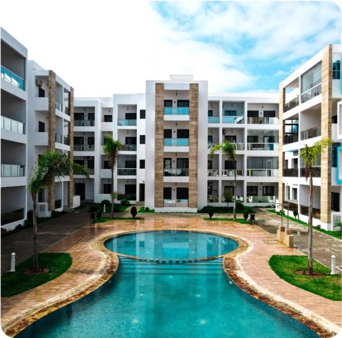 マルティルにあるAppartement haut standing 2 chambres piscine Martilの大きなアパートメントの建物の前にスイミングプールがあります。