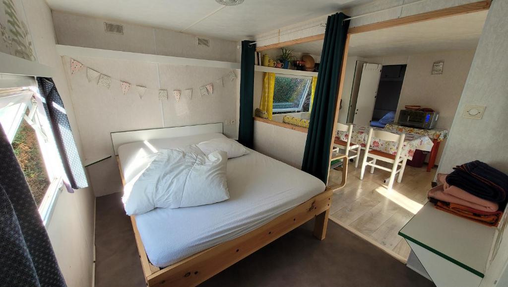 Un pequeño dormitorio con una cama en una casa diminuta. en Mobile home toutes saisons, en Beauzac