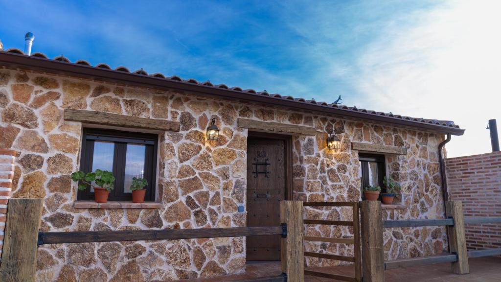 a stone house with two windows and potted plants at La Casita del Tejar in Cardiel de los Montes