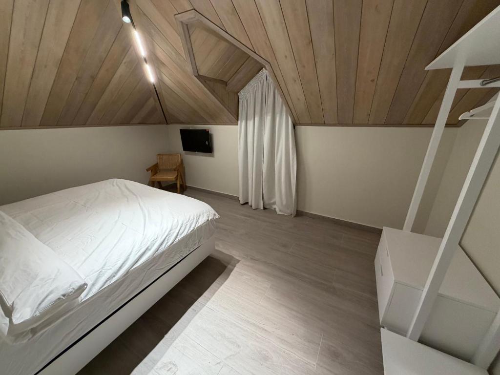 a bedroom with a white bed and a wooden ceiling at EYZ Lofts By EYZ Holiday Homes in Batroûn