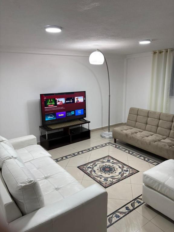 ロハにあるCasa Moderna en Loja - ideal para familiasの白い家具と薄型テレビのあるリビングルーム