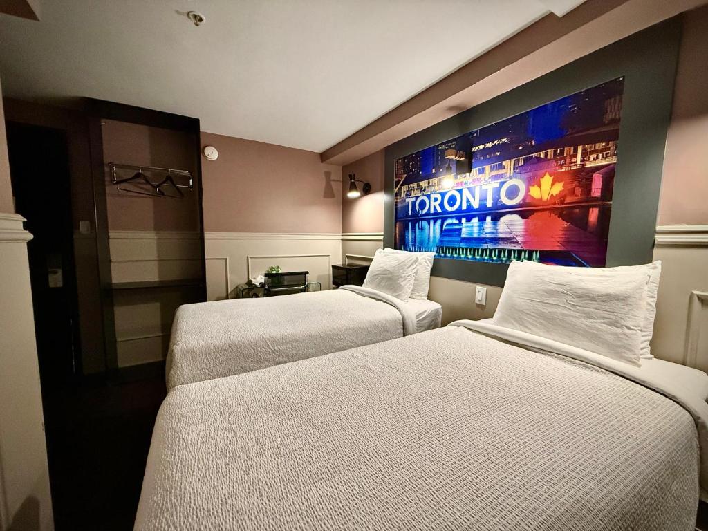 two beds in a hotel room with a large screen at Royal Oak Inn in Toronto