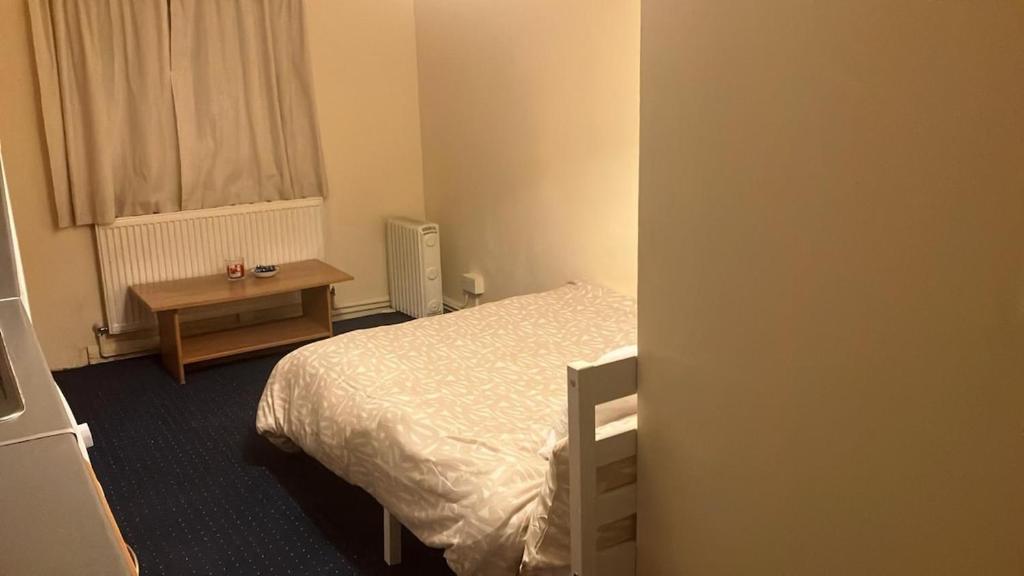 ein kleines Schlafzimmer mit einem Bett und einem Tisch in der Unterkunft Charming Garden Guest House in Hayes & Harlington in Hayes