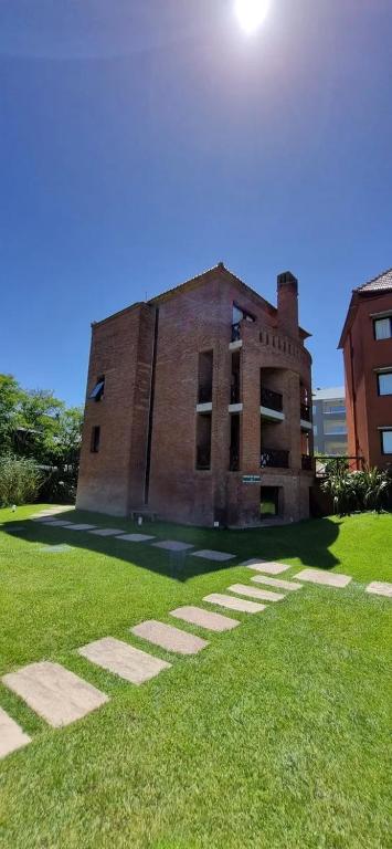 an old brick building on a field of grass at Club carilo playa Edificio del bosque in Carilo