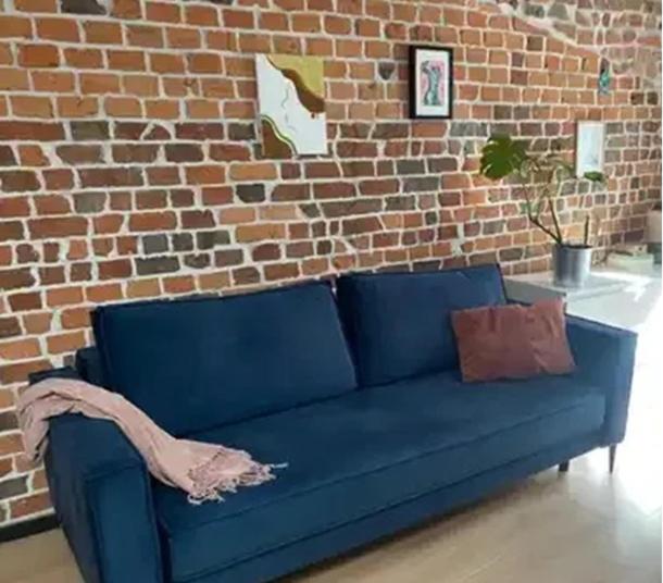a blue couch in front of a brick wall at Warszawska in Toruń