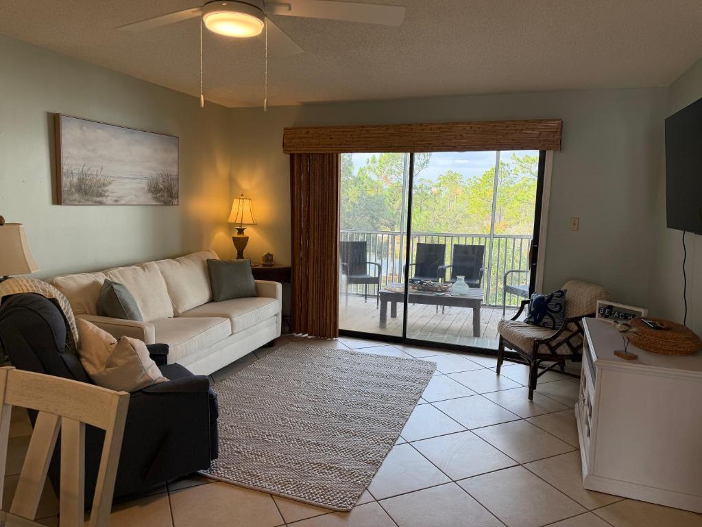 a living room with a couch and a table and a balcony at Latitude 302 in Orange Beach