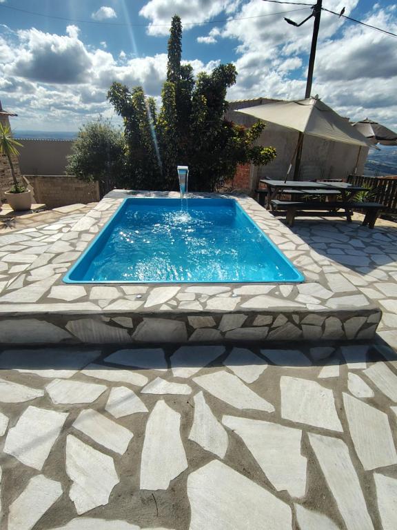 een zwembad met een fontein op een patio bij Recanto das Pedras hospedagem- Loft Container in São Thomé das Letras