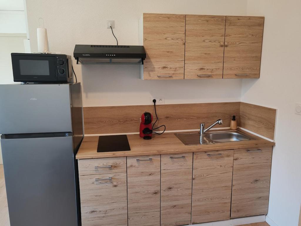 Cosy appartement calme et tout équipé idéal seul ou en couple في Seloncourt: مطبخ صغير مع ثلاجة ومغسلة