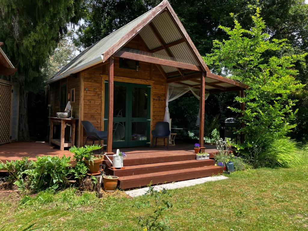 a small wooden cabin with a deck and a desk at RIMU CABIN At the Bridge in Motungarara