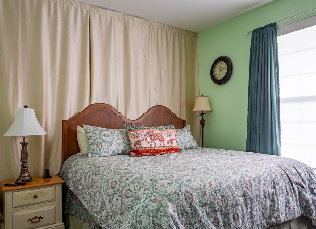 Un dormitorio con una cama y un reloj en la pared. en Azure Elephant Haven - 2 King Suites in Bayberry South, en Middletown