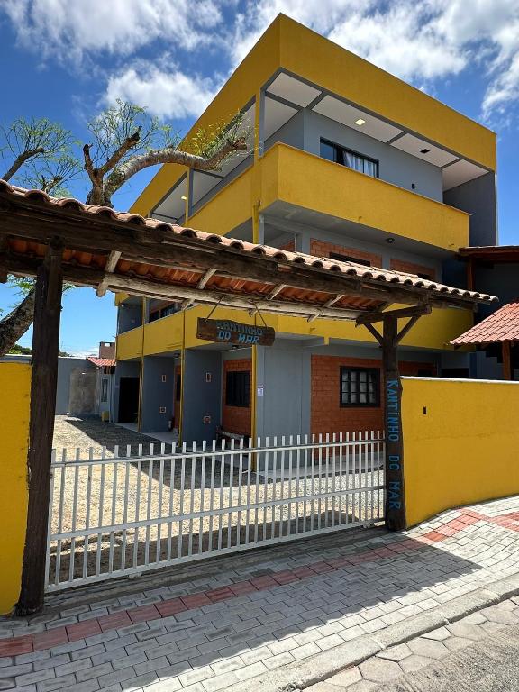 a yellow building with a white fence in front of it at Kantinho do Mar in São Francisco do Sul