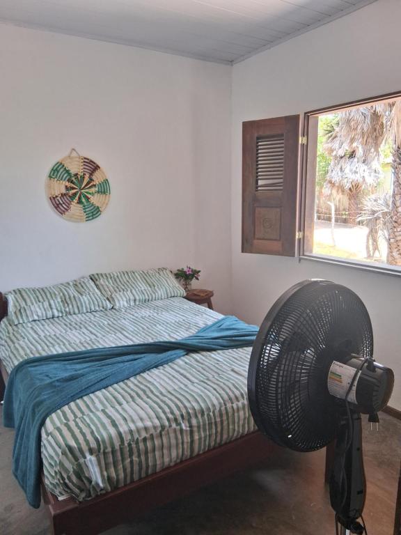 een slaapkamer met een bed en een ventilator naast een raam bij Casa Beleza Atins in Atins