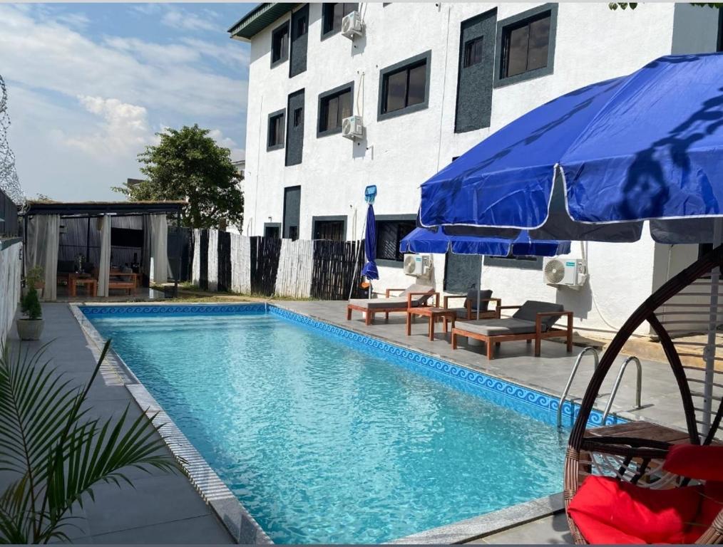 una piscina con sombrilla azul junto a un edificio en Cozy home wuye, en Abuja