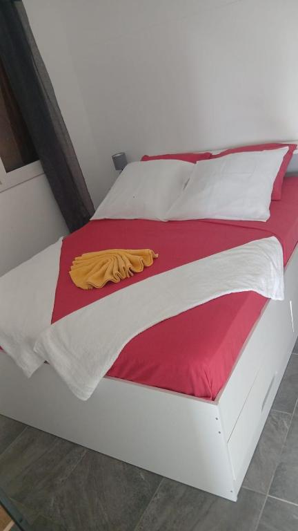 a white bed with a red and white blanket on it at An kan la in Capesterre