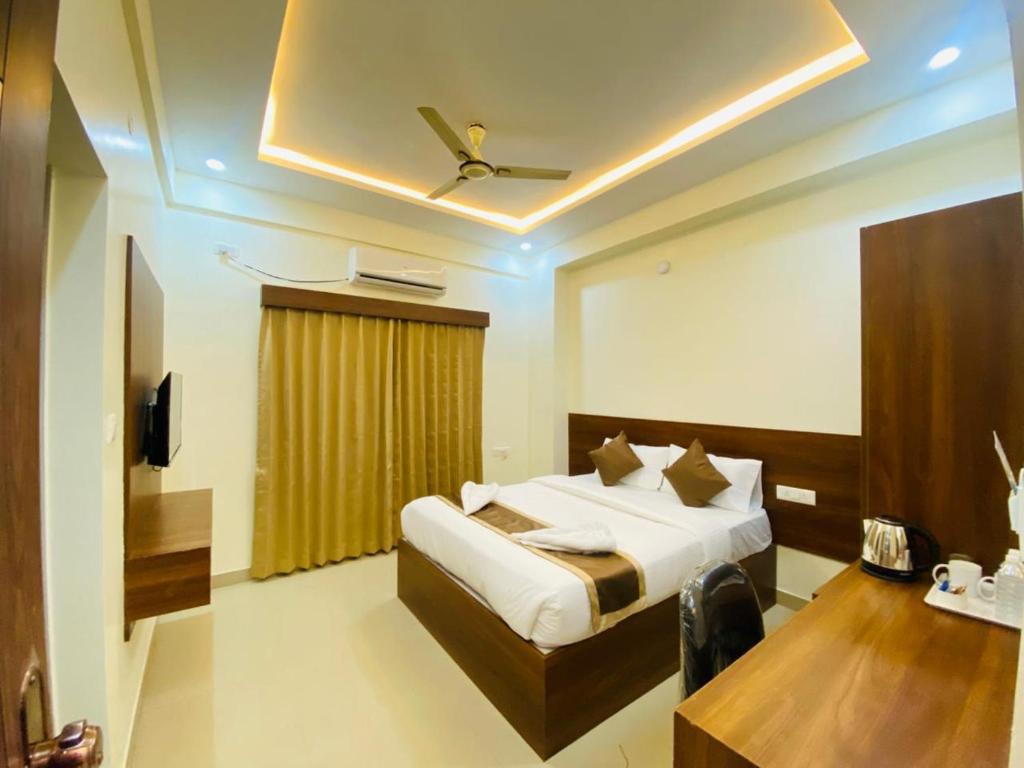 a bedroom with a bed and a table and a ceiling at Hotel SAFKO Grand - Hopefarm Metro Whitefield in Bangalore