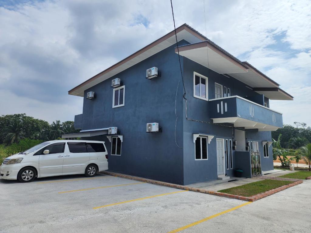 Un edificio azul con una camioneta blanca estacionada en un estacionamiento. en Homestay Warisan Iman, en Klang