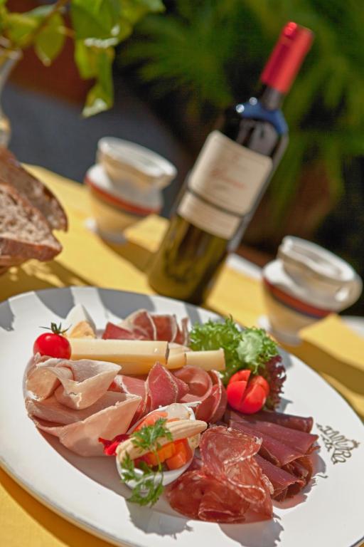 a plate of meat and cheese and a bottle of wine at Hotel Tamaro in Ascona
