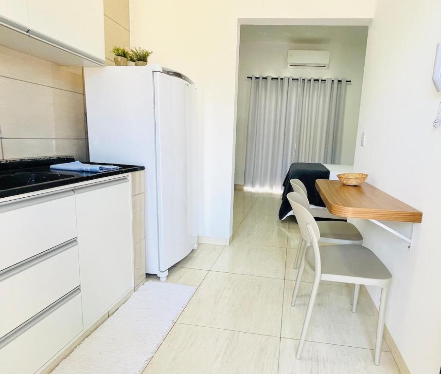 a kitchen with a table and a white refrigerator at Compras no Paraguai e pesca no Rio Paraná! in Guaíra