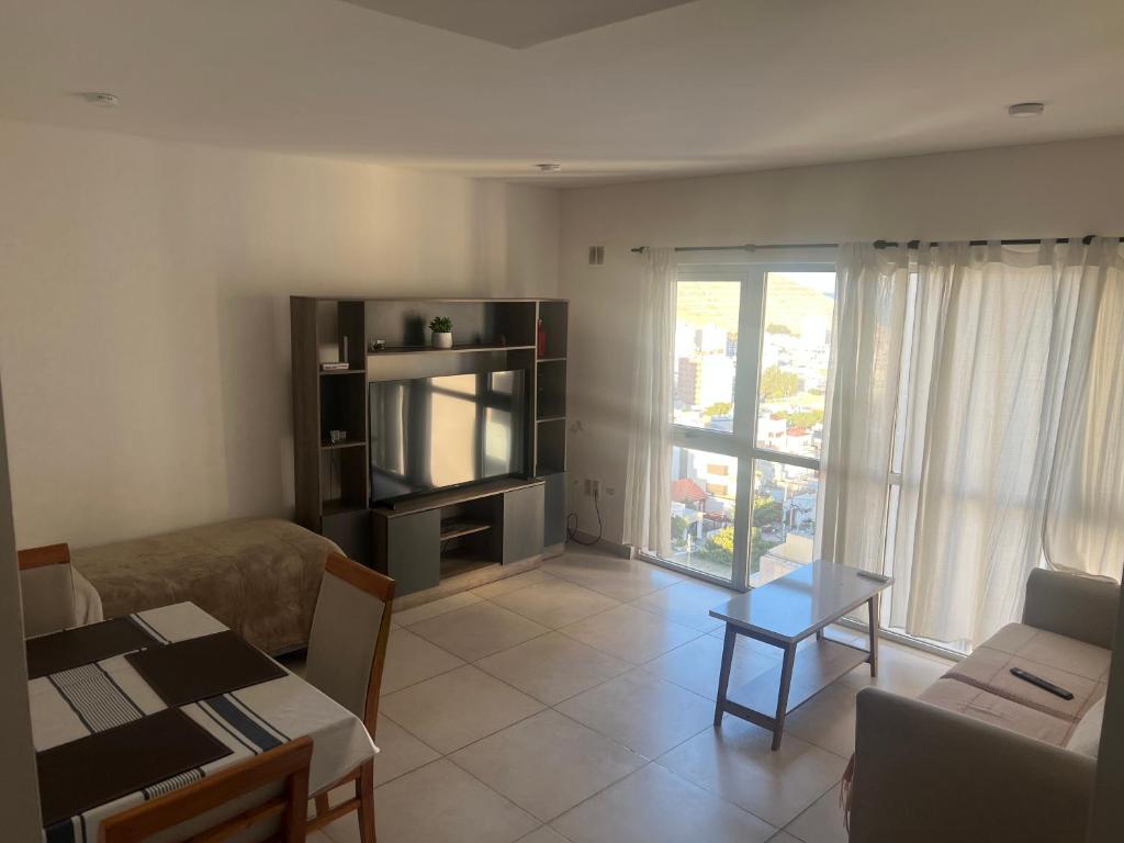 ein Wohnzimmer mit einer Couch, einem Fernseher und einem Tisch in der Unterkunft Sueños del Sur, moderno departamento in Comodoro Rivadavia
