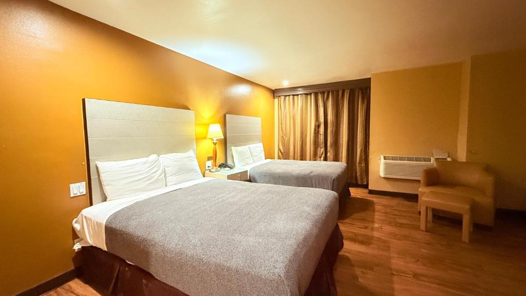 a hotel room with two beds and a chair at Redondo Beach Inn-LAX in Gardena