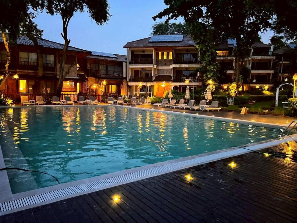 een zwembad 's nachts met een hotel op de achtergrond bij Birds and Bees Resort in Pattaya South