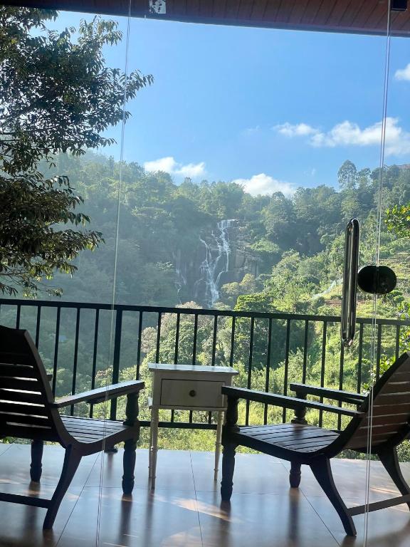 a balcony with two chairs and a view of a waterfall at Ella waterfall view in Ella
