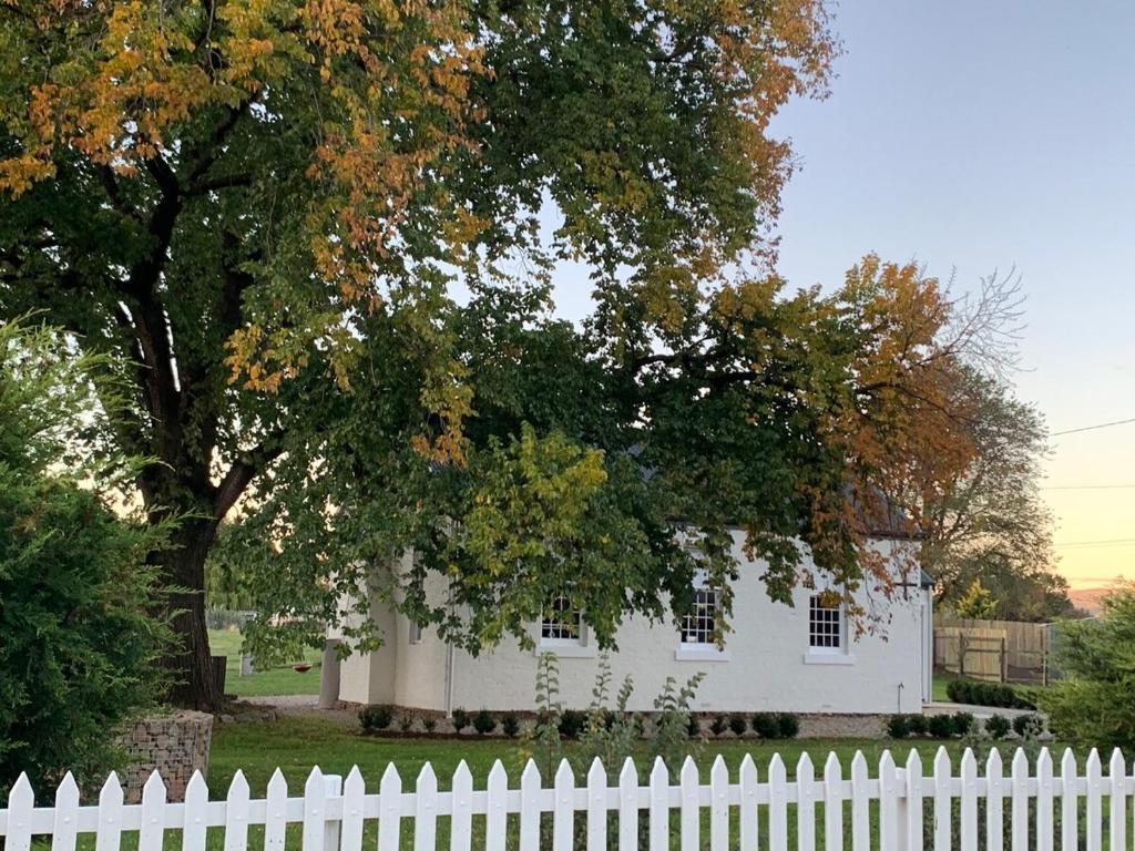a white fence in front of a white house with a tree at The Ol' Sunday School in Ross
