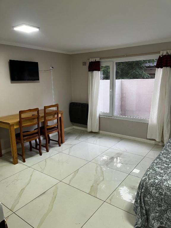 een woonkamer met een tafel, stoelen en een televisie bij Líbano flat in El Bolsón