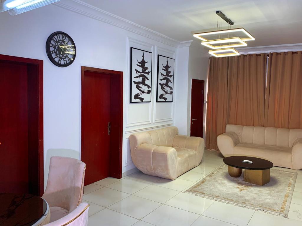 uma sala de estar com sofás e um relógio na parede em Cavalli apartment em Hausa