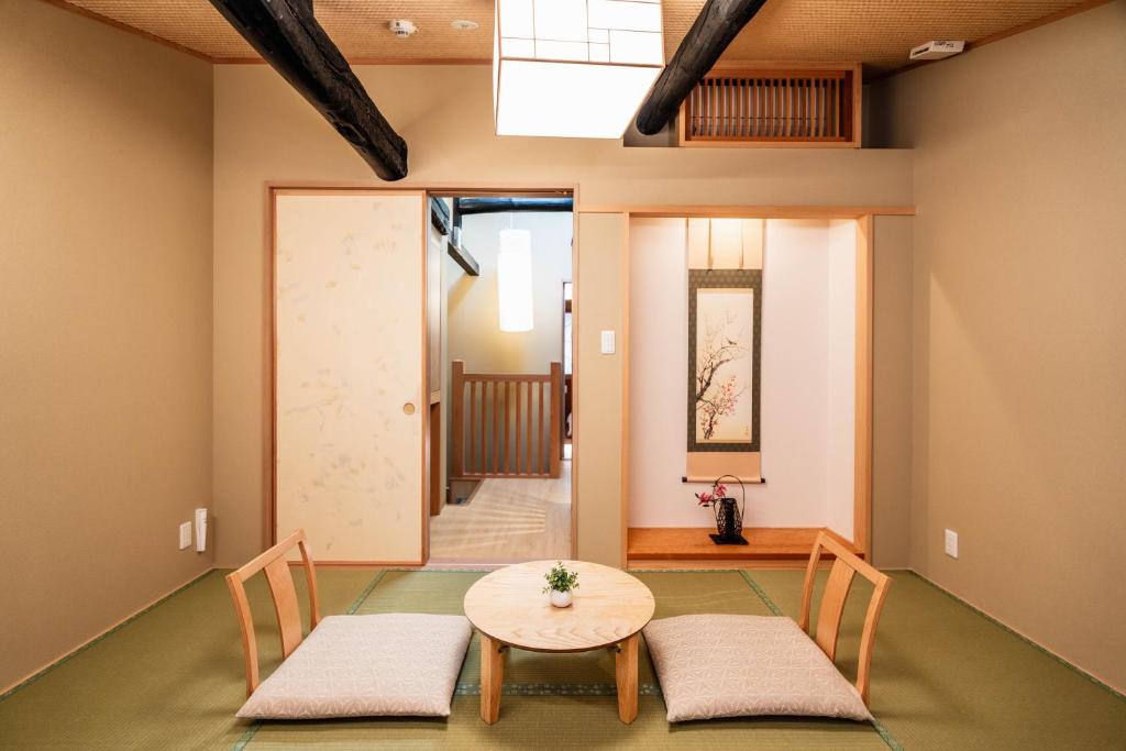 - une chambre avec deux chaises, une table et une porte dans l'établissement Machiya Izumi higashiyama, à Kyoto