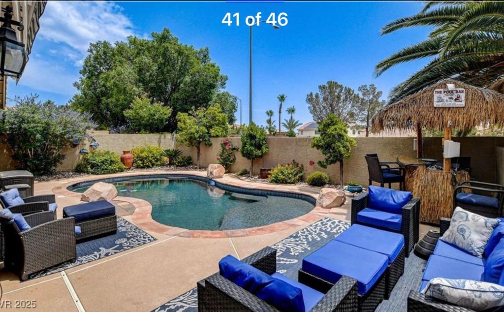 a backyard with a pool with chairs and a table at Amazing Grace Vacation Home in Las Vegas