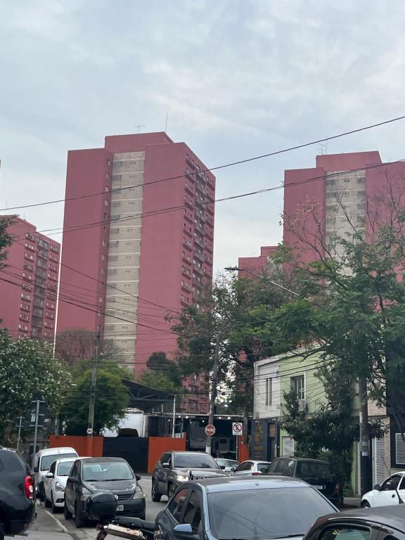 a street with cars parked in front of tall buildings at Pé na festa in Aracati