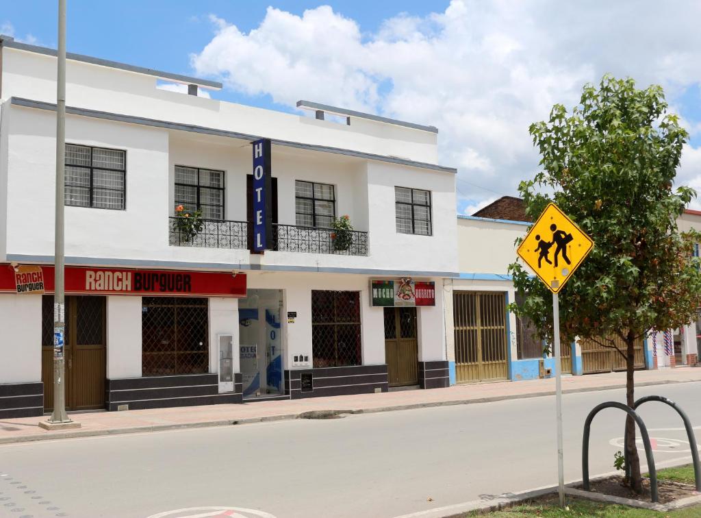 un edificio blanco en una calle con una señal de cruce peatonal en Hotel Abadia en Sogamoso