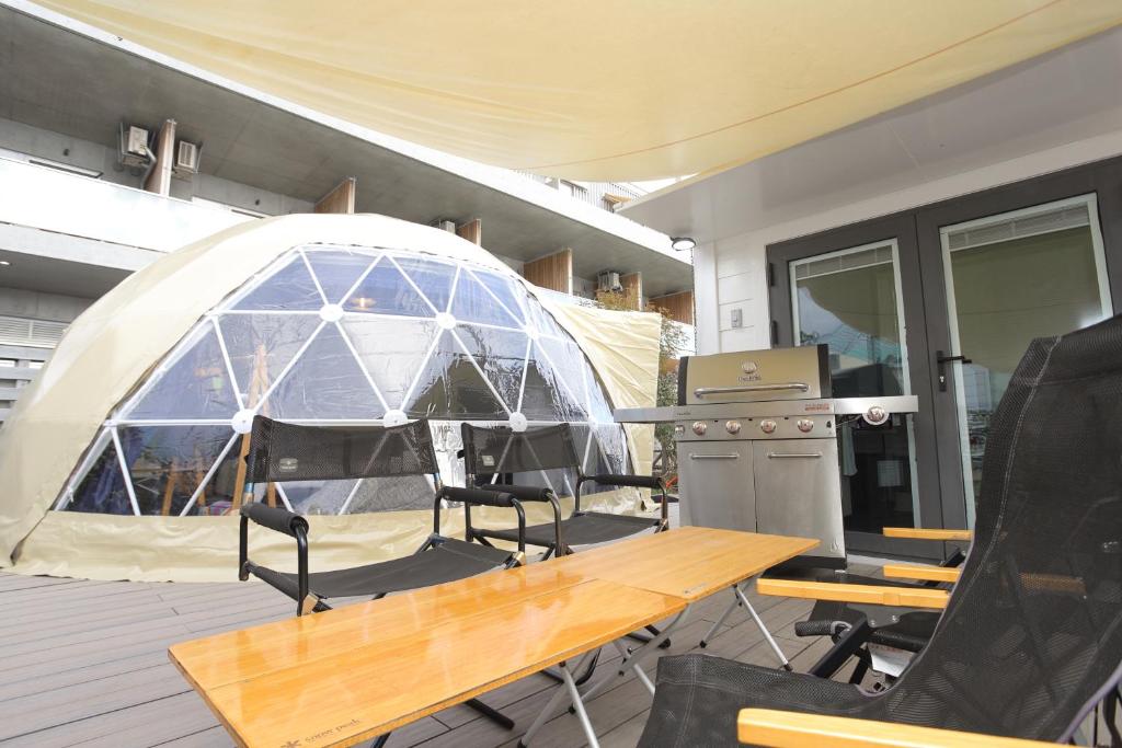 Una tienda de campaña en una terraza con una mesa y sillas. en Fukiagehama Field Hotel, en Ichikikushikino