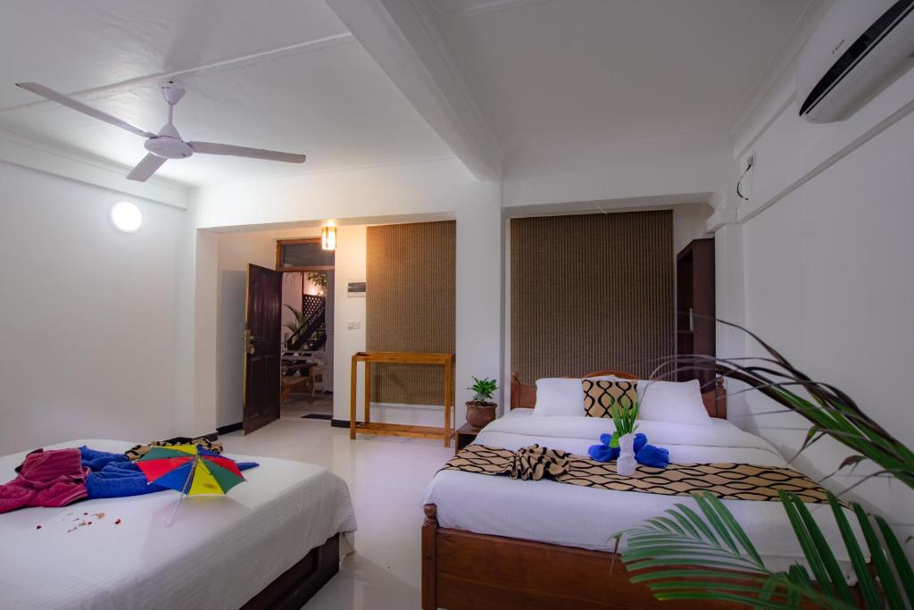 a bedroom with two beds and a ceiling fan at Hotel Surf Resort in Arugam Bay