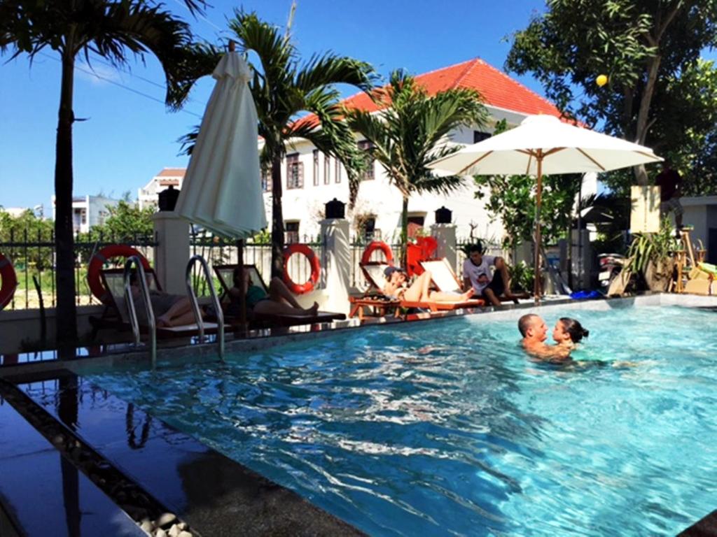 een man en een kind in het zwembad van een resort bij Unity Villa in Hội An