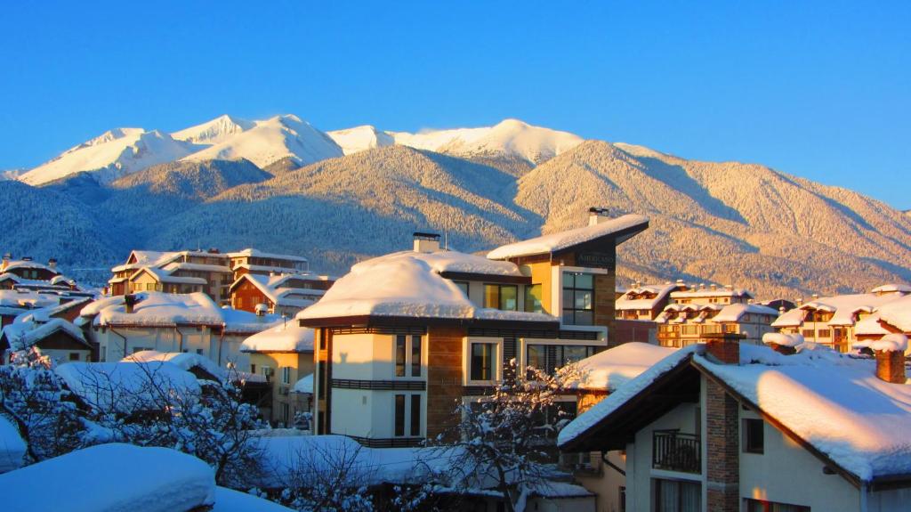 a town covered in snow with mountains in the background at Family Hotel Santo Bansko in Bansko