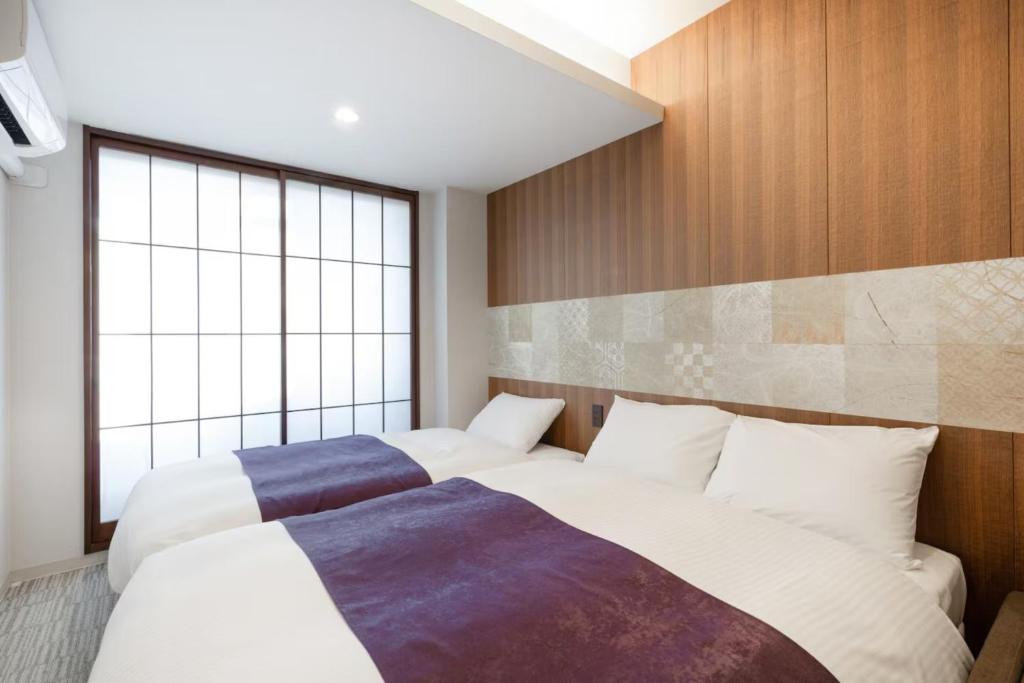 een slaapkamer met twee bedden en een groot raam bij Irori Kyoto Station Higashi-Honganji in Kyoto