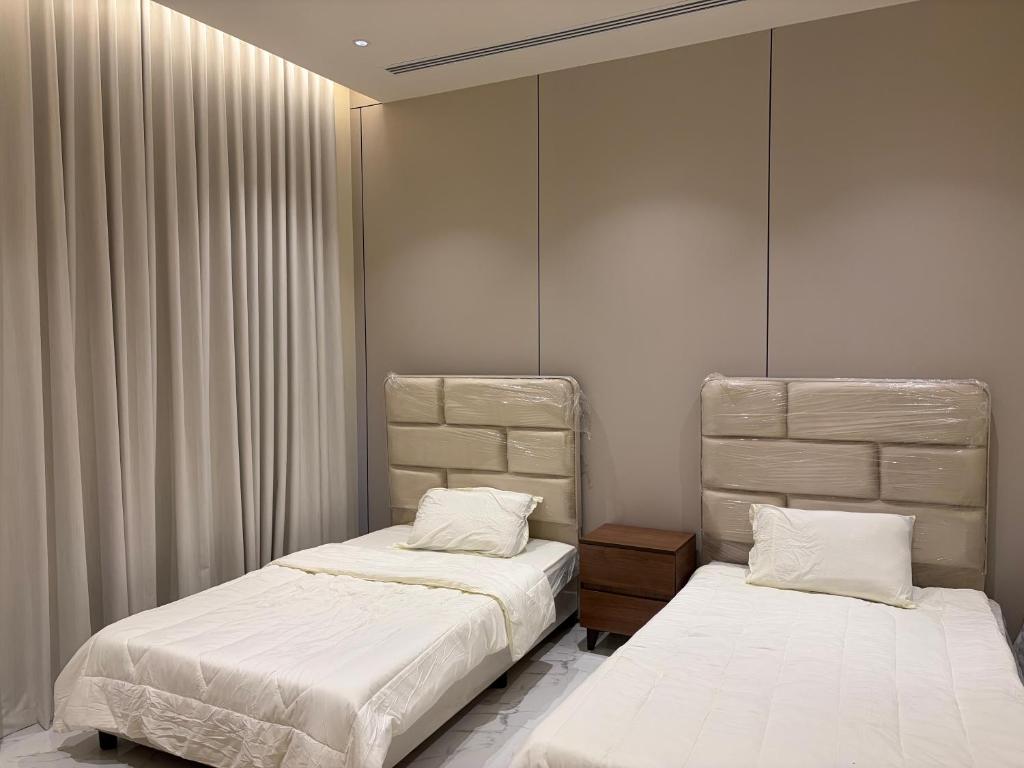 2 letti in una camera con pareti e tende bianche di شاليه وجد a Shaqra