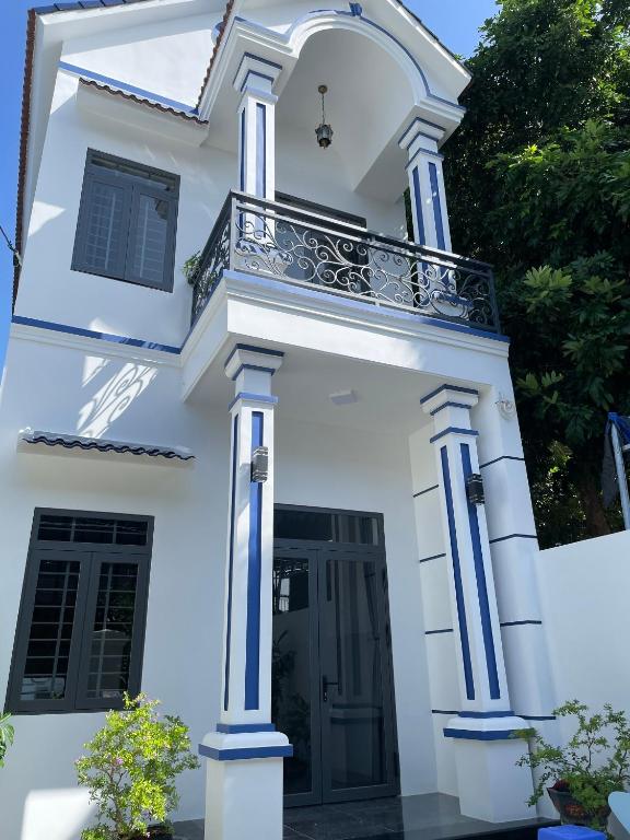 a white house with blue columns and a balcony at Habi Homestay Doc Let in Phú Thọ